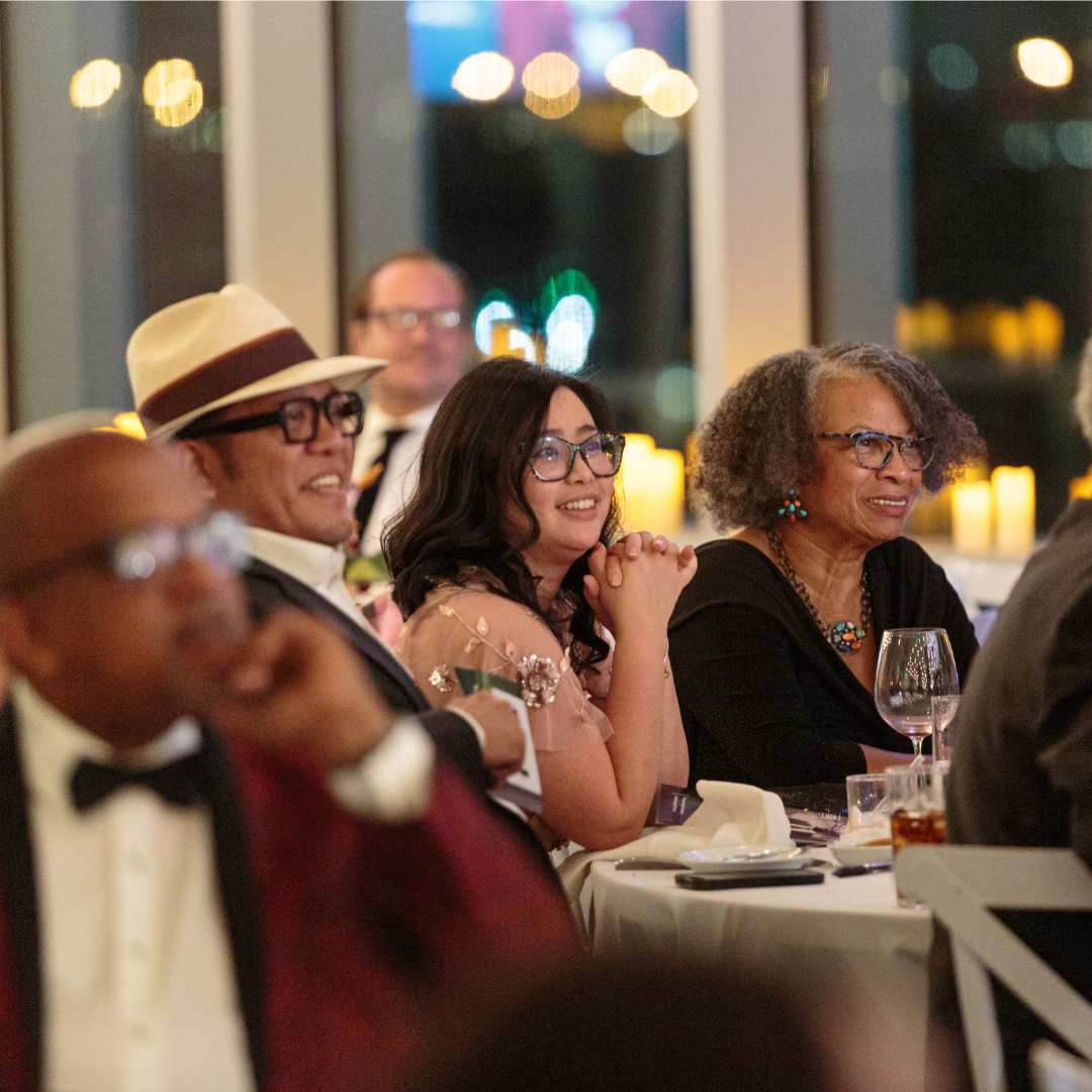 People smiling sitting at a table at a gala